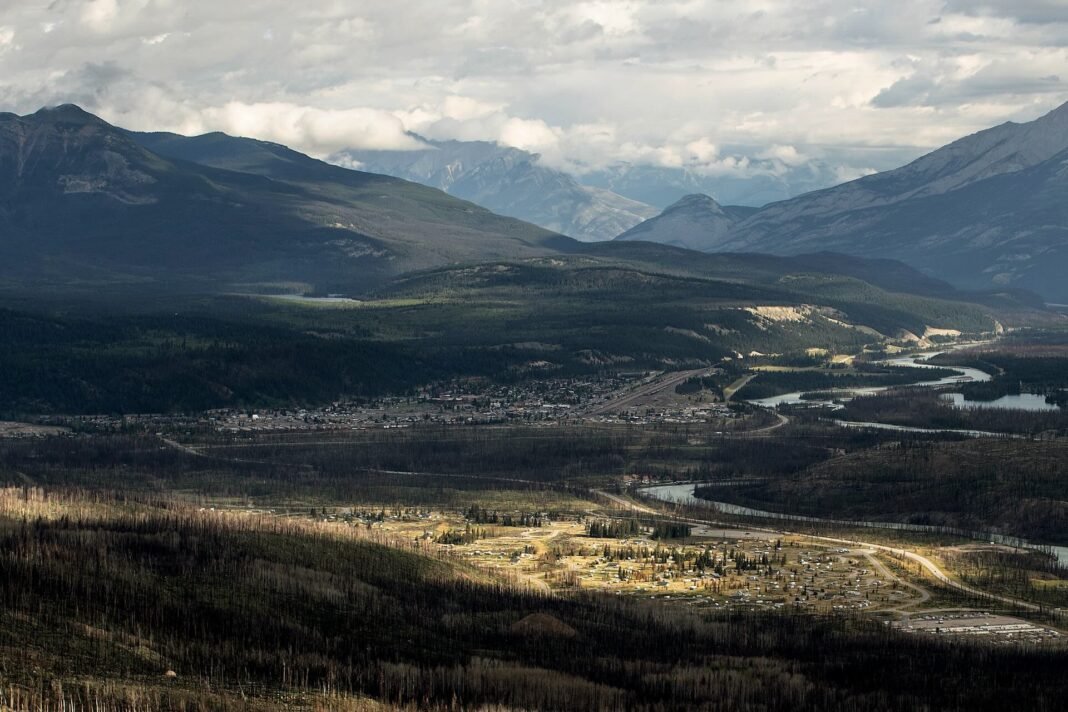 A landscape shot of a small town surrounded by tress and rivers, with mountains in the background.