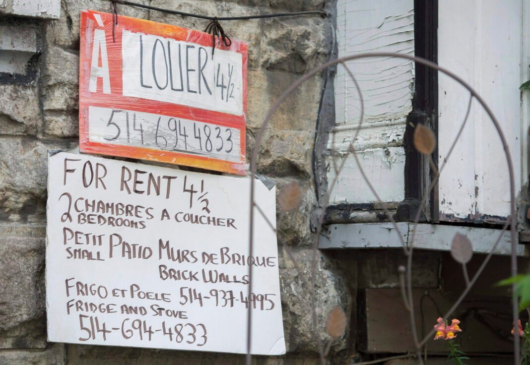 Stone façade of a building with two signs advertising a 4½ apartment for rent. One is an orange “For rent” sign; the other is a handwritten notice with details.